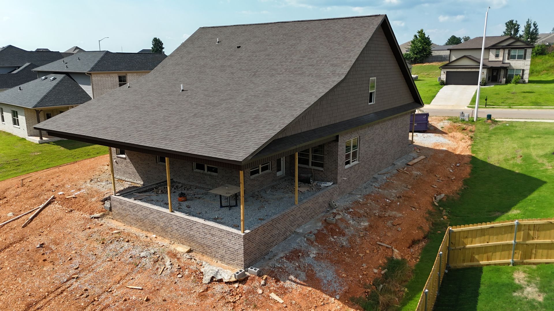 New home under construction with brick facade and dark roof.