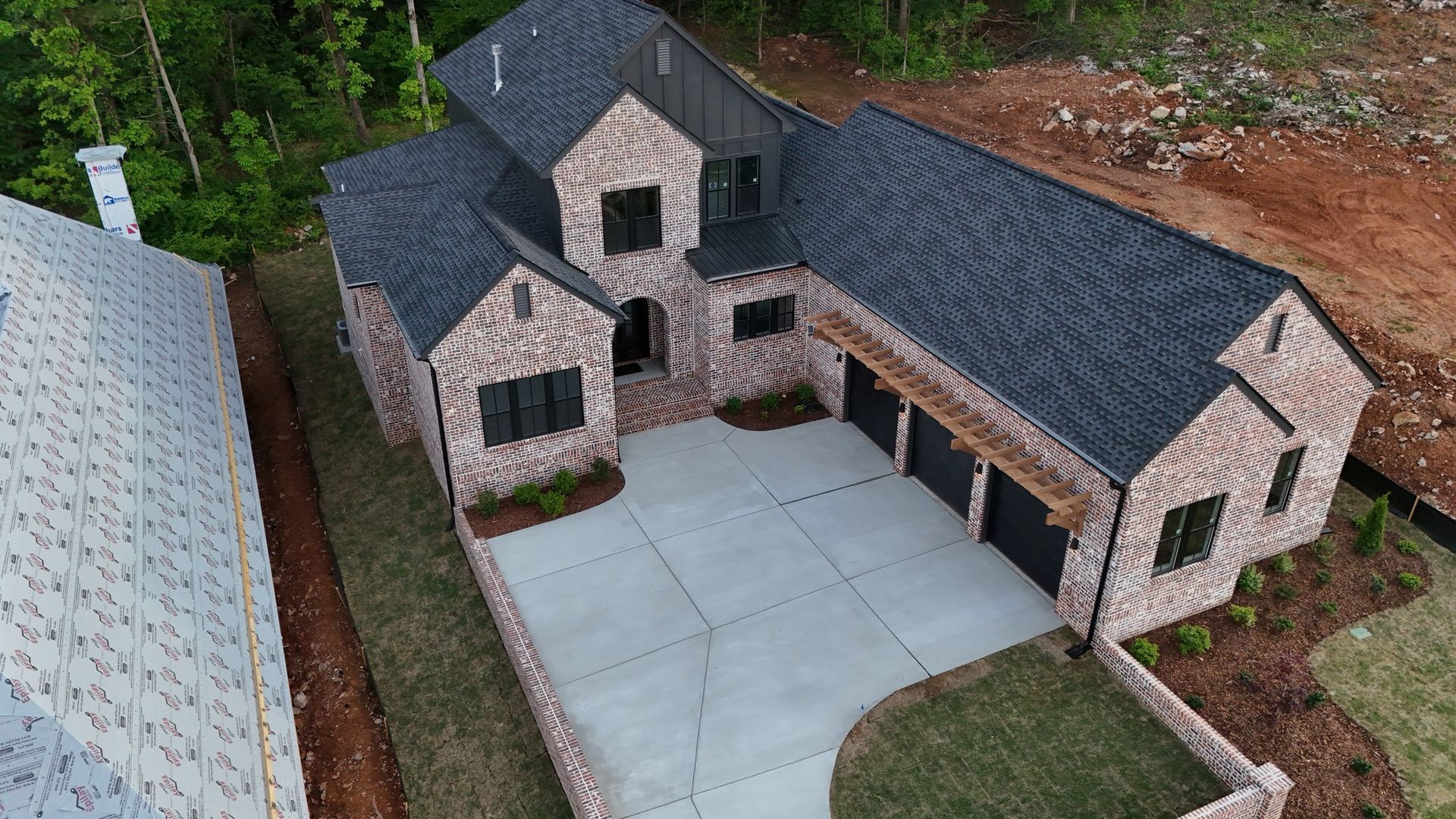 Brick house with a dark roof and a three-car garage. A concrete driveway leads up to the house.