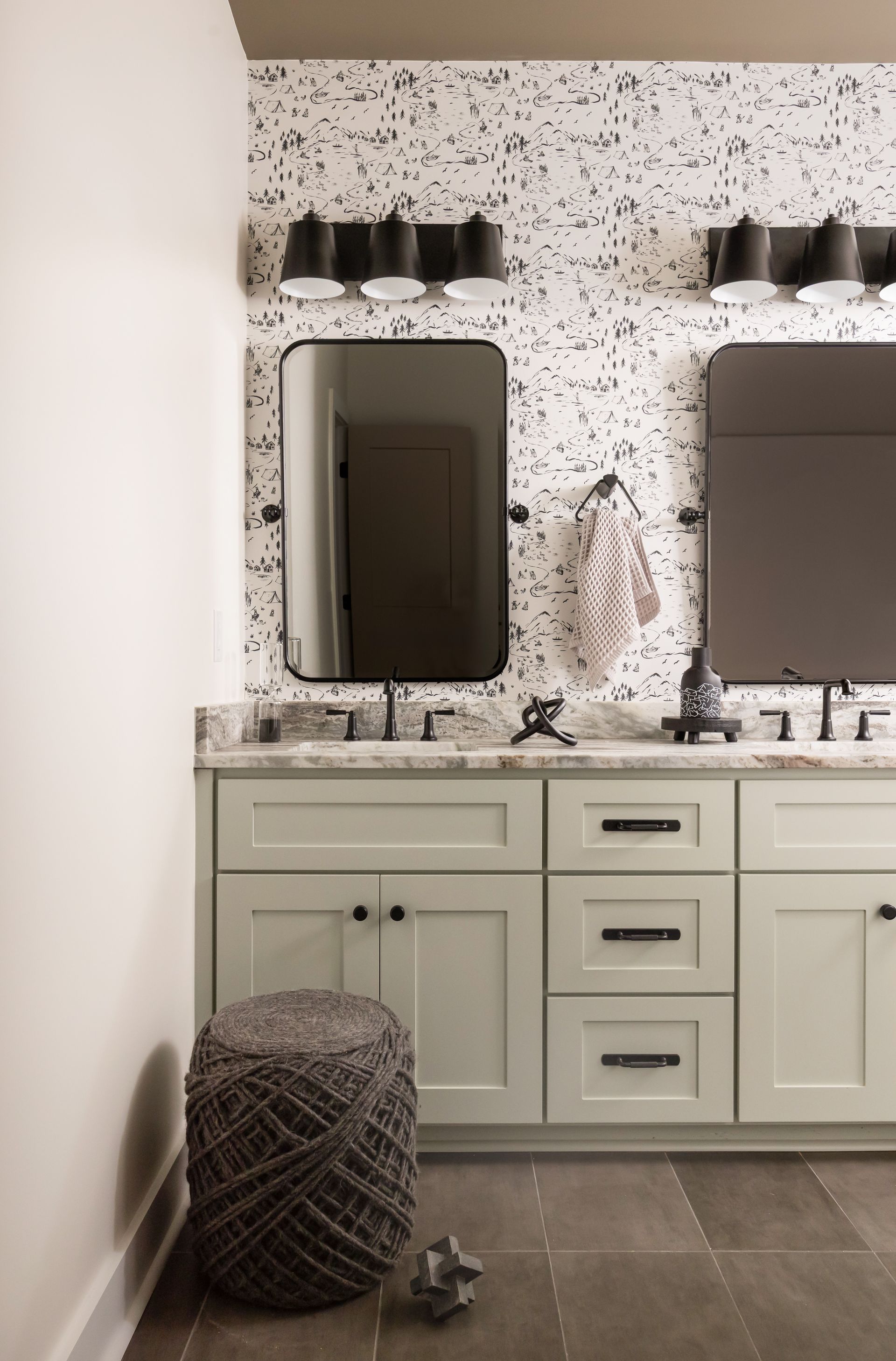 Bathroom with a vanity, two mirrors, and a speckled accent wall.