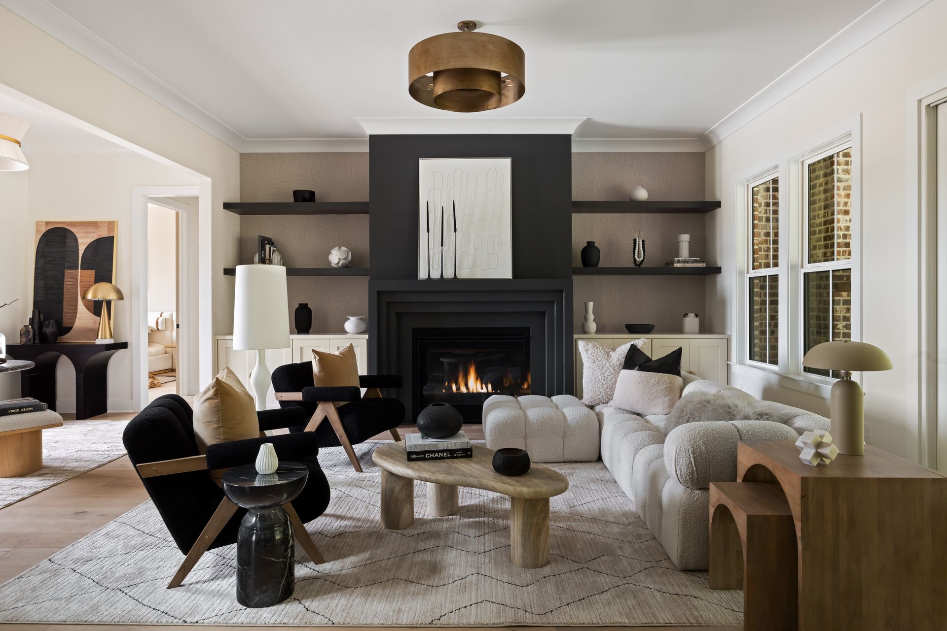 Living room with fireplace, shelving, black and neutral furniture, rug.