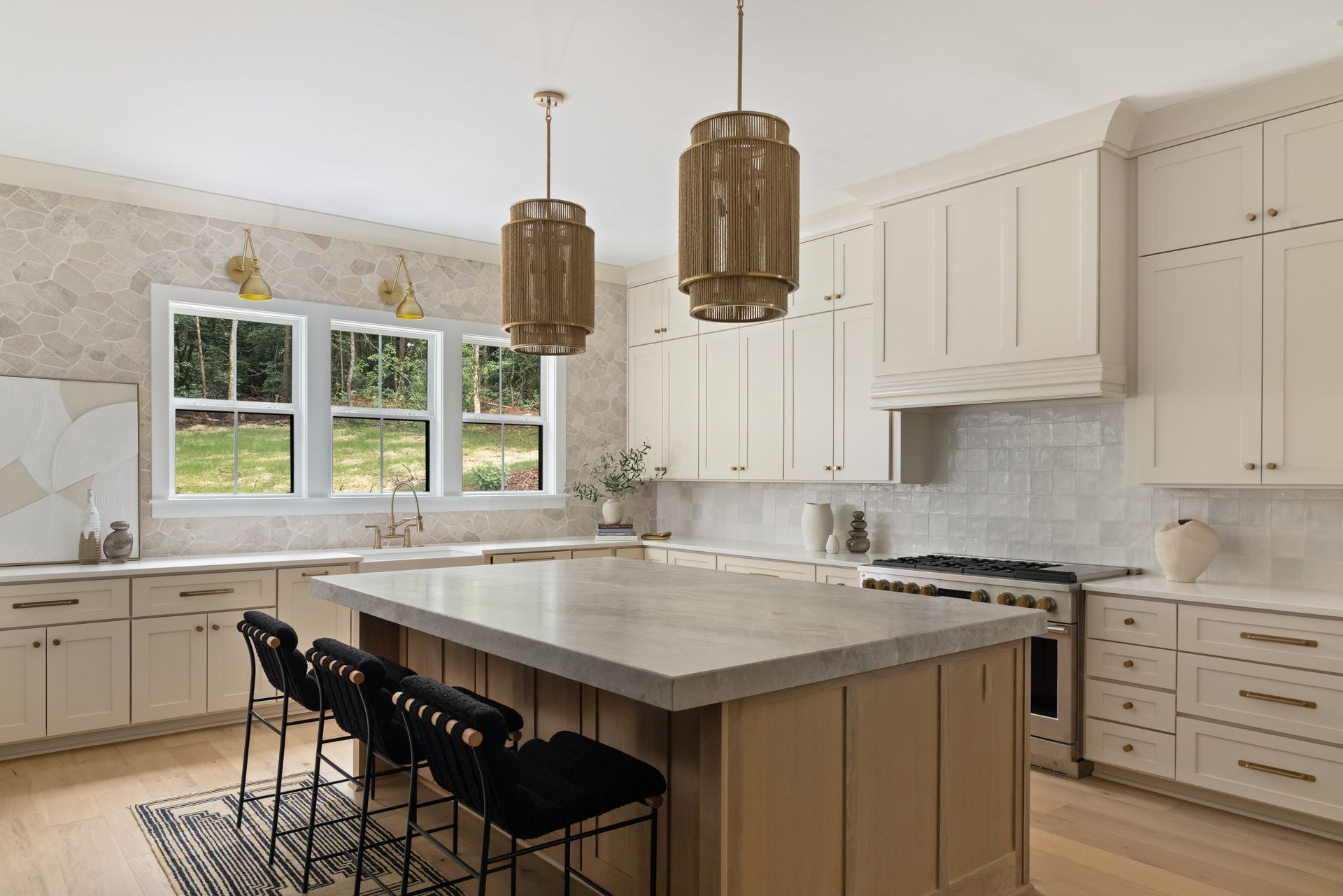 Modern kitchen with white cabinets, island, stone backsplash, and pendant lights.