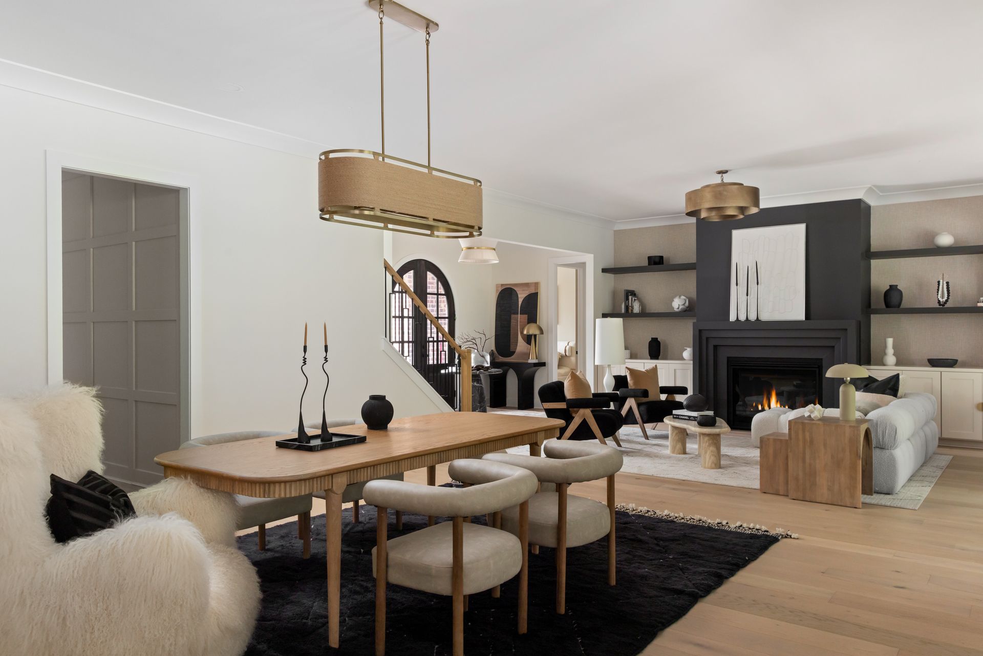 Open-plan living room with dining area. Features a fireplace, dining table, and seating with neutral color tones.