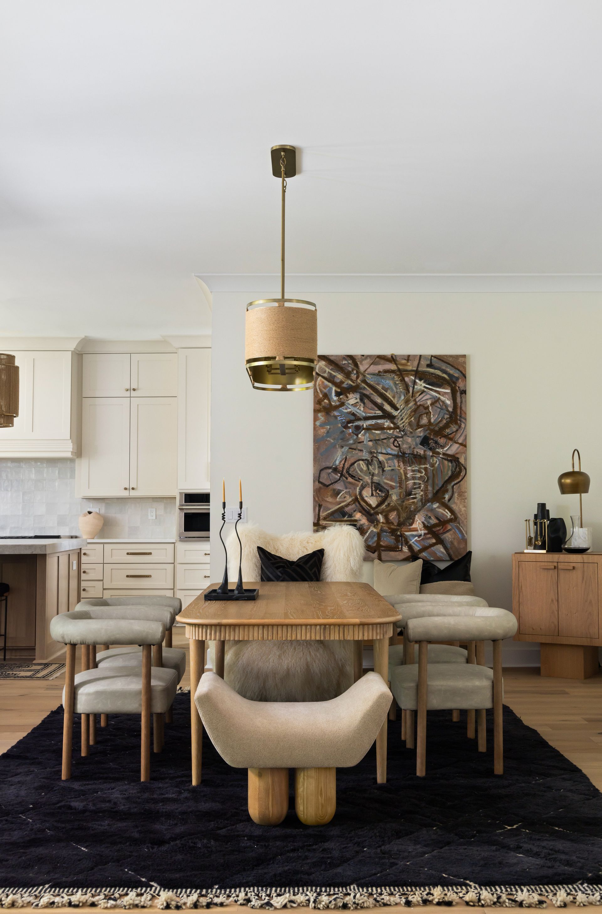 Dining room with a wooden table, chairs, art, and a dark blue rug.