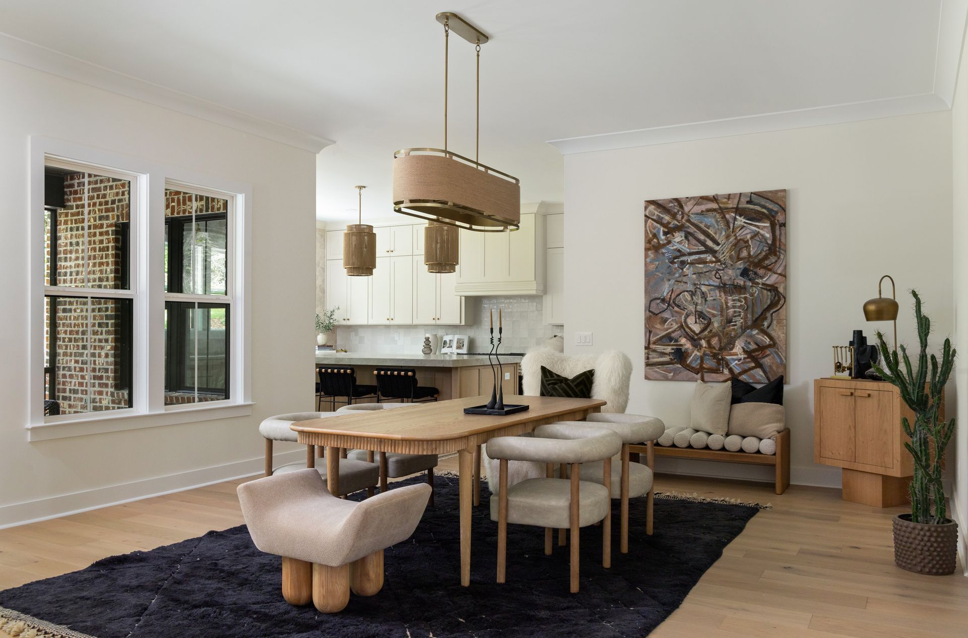 Dining room with wooden table, chairs, artwork, and light fixture. Light wood flooring and neutral walls.