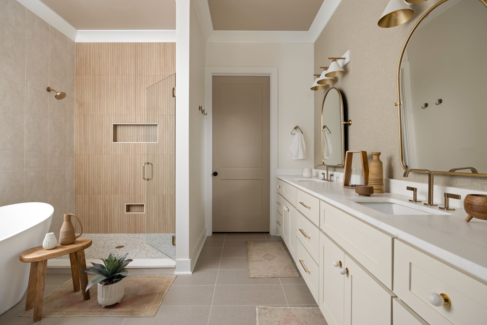 Bathroom with beige and wood tones. Shower, vanity, and freestanding tub. Gold fixtures.