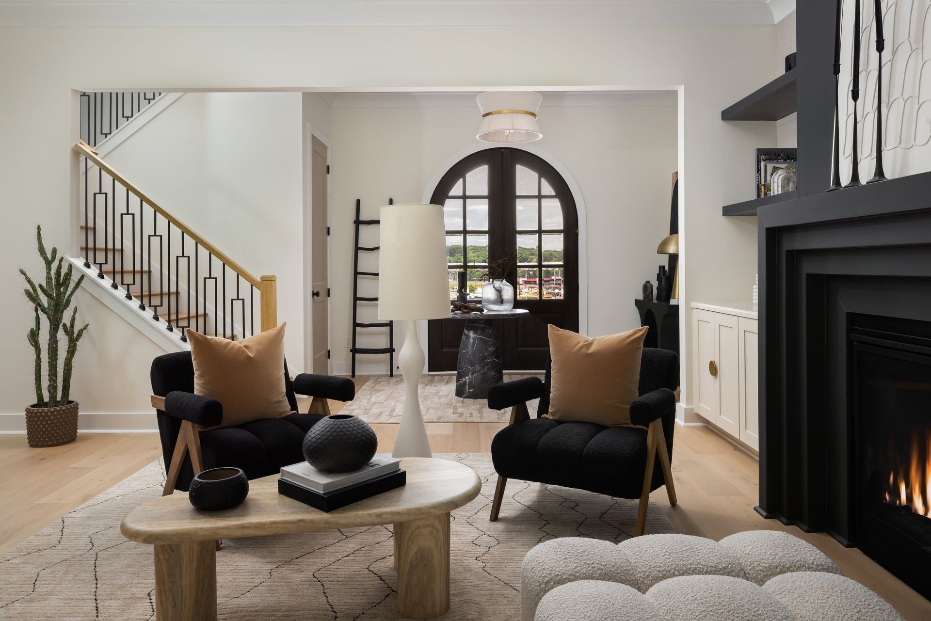Living room with black armchairs, tan pillows, and fireplace.