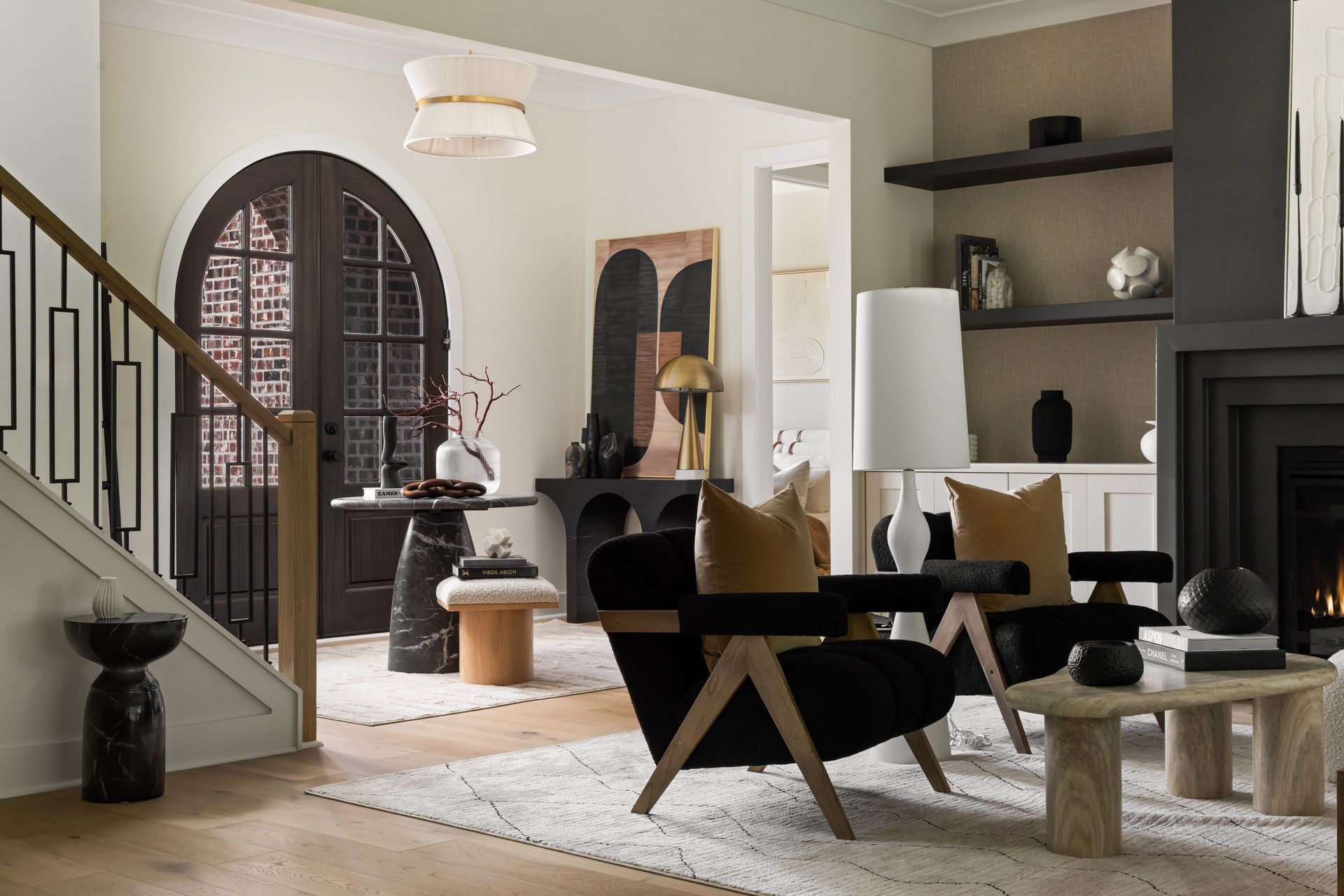 Living room with arched doorway, black furniture, and neutral decor.