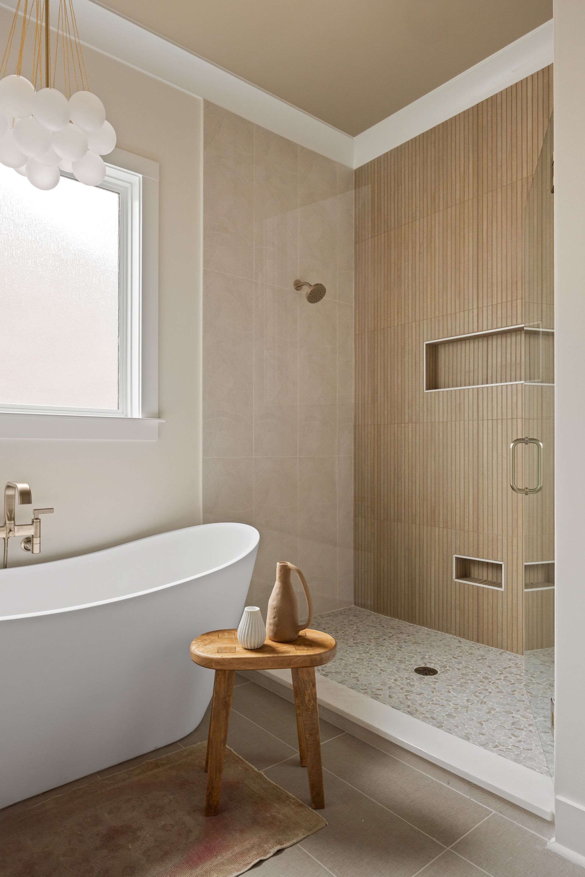 Bathroom with a white bathtub, a wooden stool, and a shower with wooden paneling.