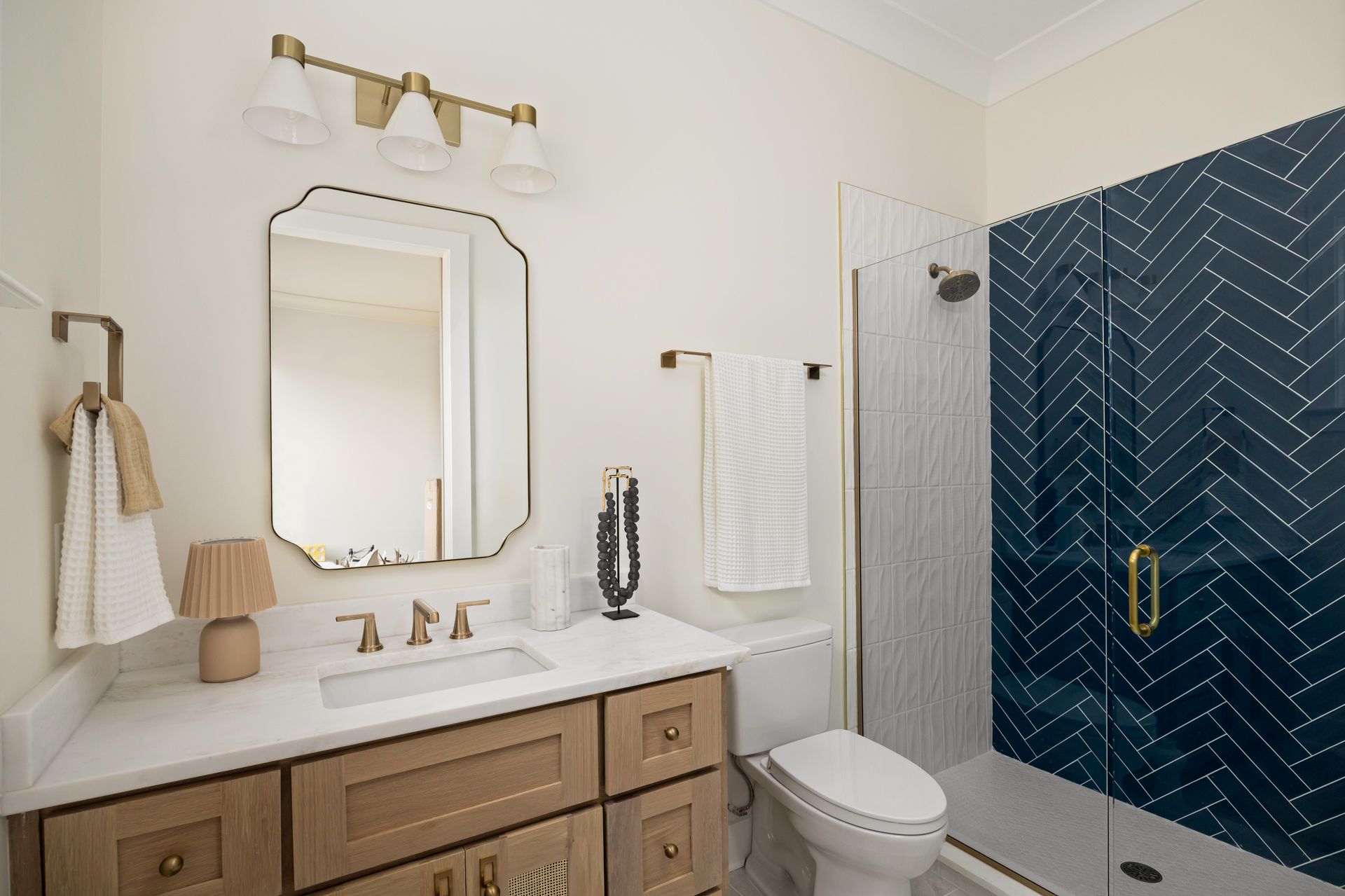 Bathroom with a blue tiled shower, a vanity with a mirror, and a toilet.