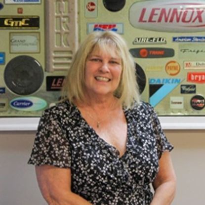 A smiling blonde woman stands in front of a wall featuring various HVAC company logos.