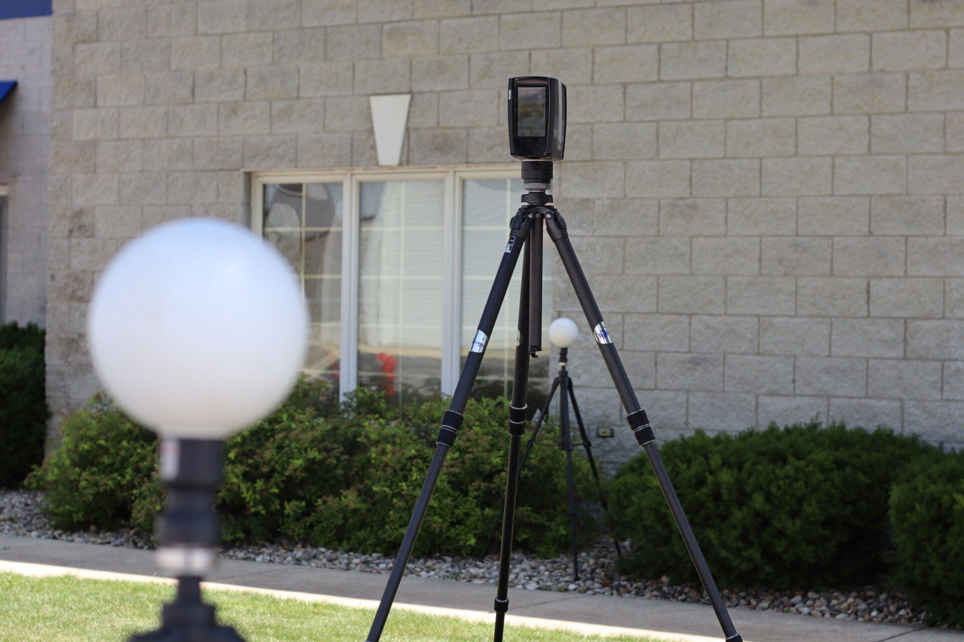 a camera is sitting on a tripod in front of a brick building.