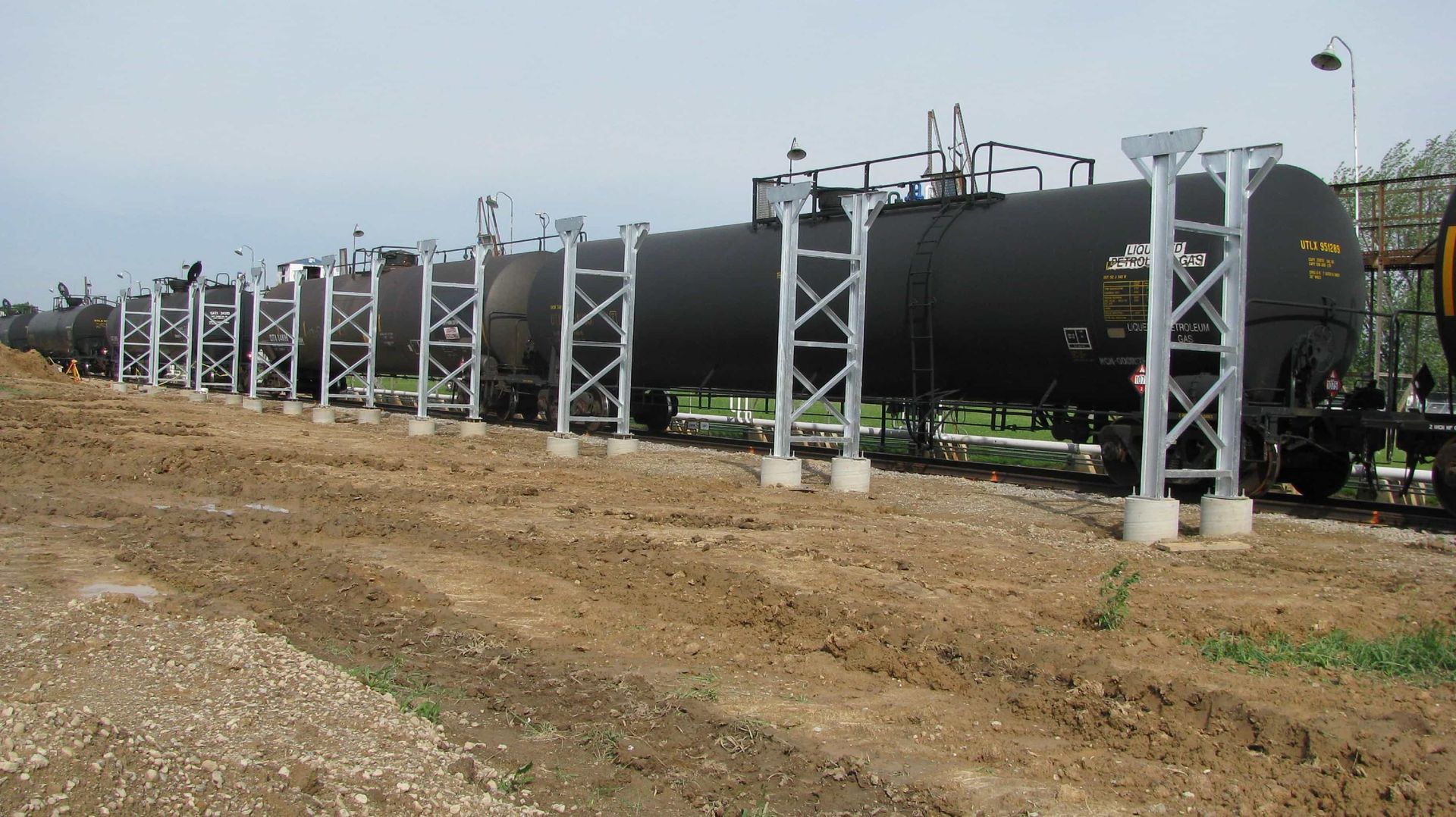a row of train cars are parked in a dirt field