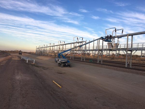 a crane is sitting on the side of a road next to a bridge .