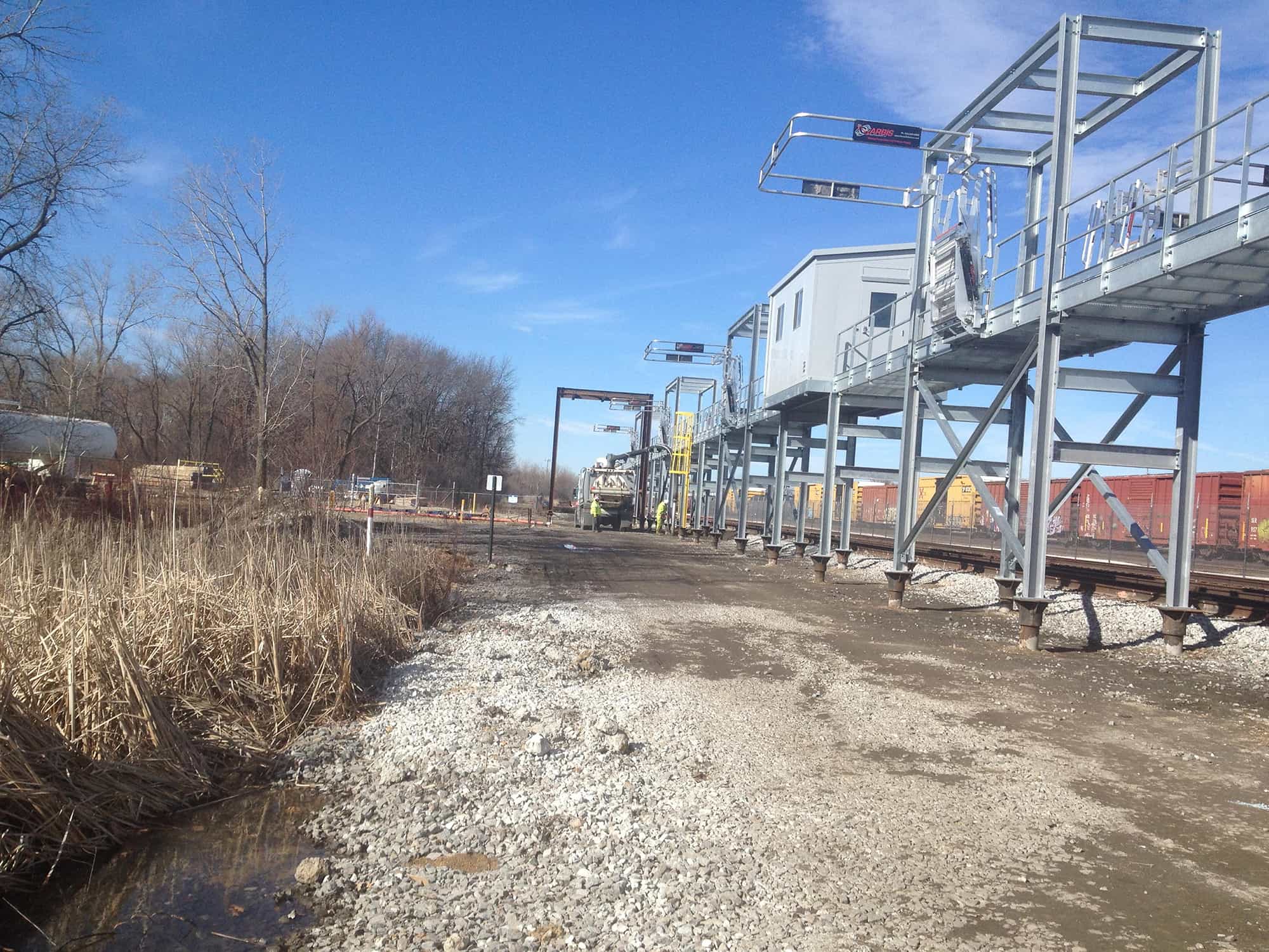 a train is going down the tracks next to a bridge .