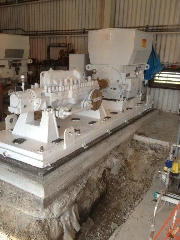 a large white machine is sitting in the dirt in a room .