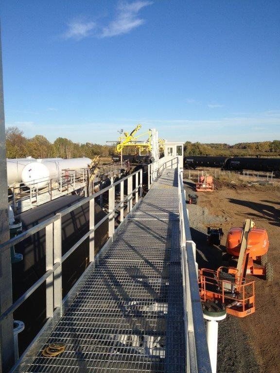 a metal walkway with a railing and a crane in the background .