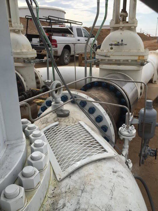a white truck is parked next to a large pipe .