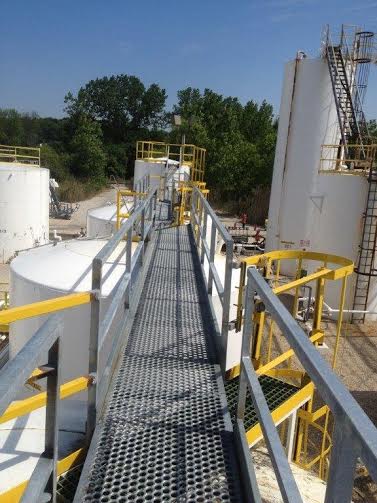 a metal walkway leading to a row of tanks in a factory .