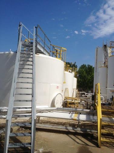 a ladder is sitting on top of a large white tank.