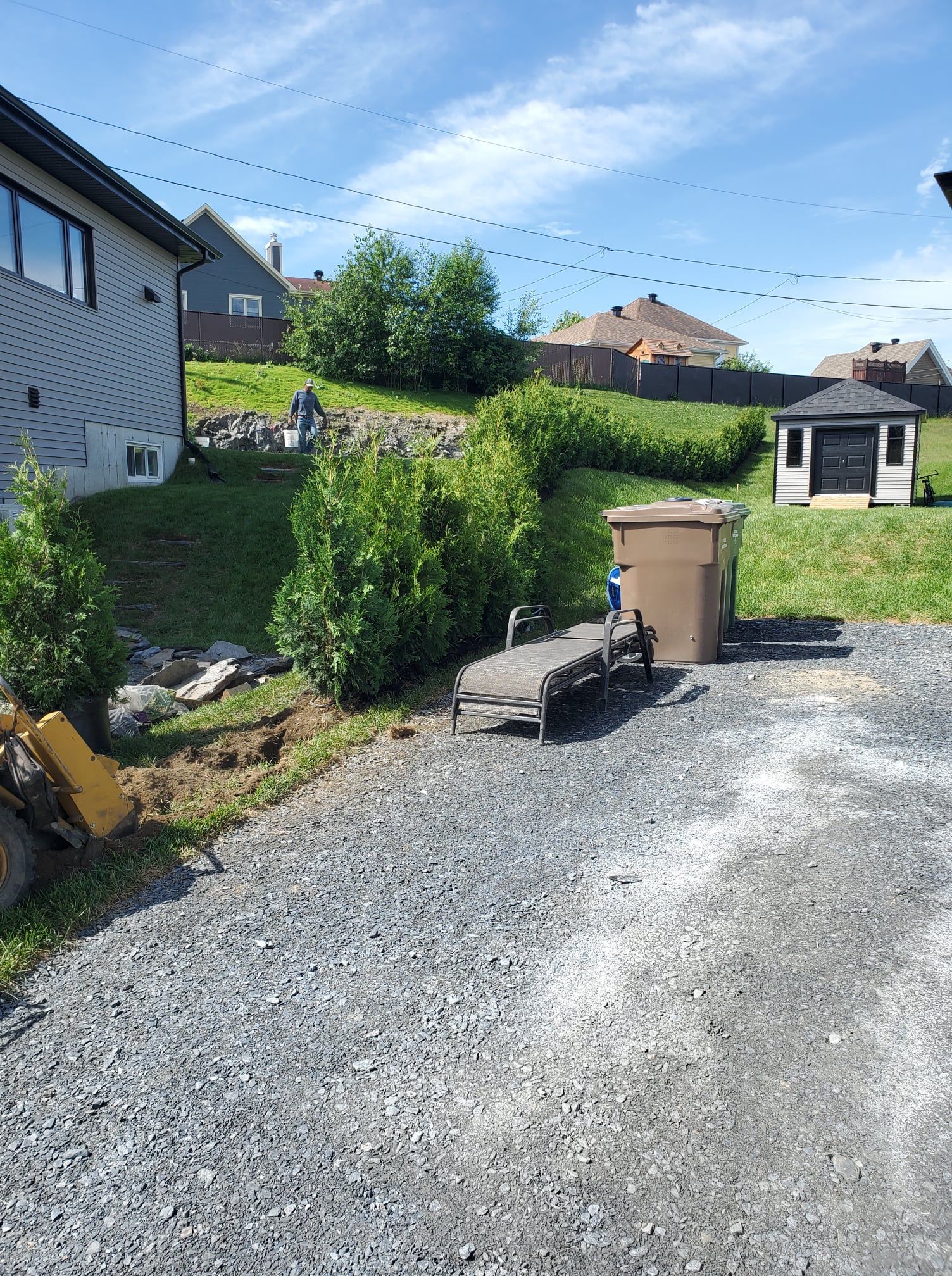 Une allée de gravier menant à une maison avec un hangar en arrière-plan.