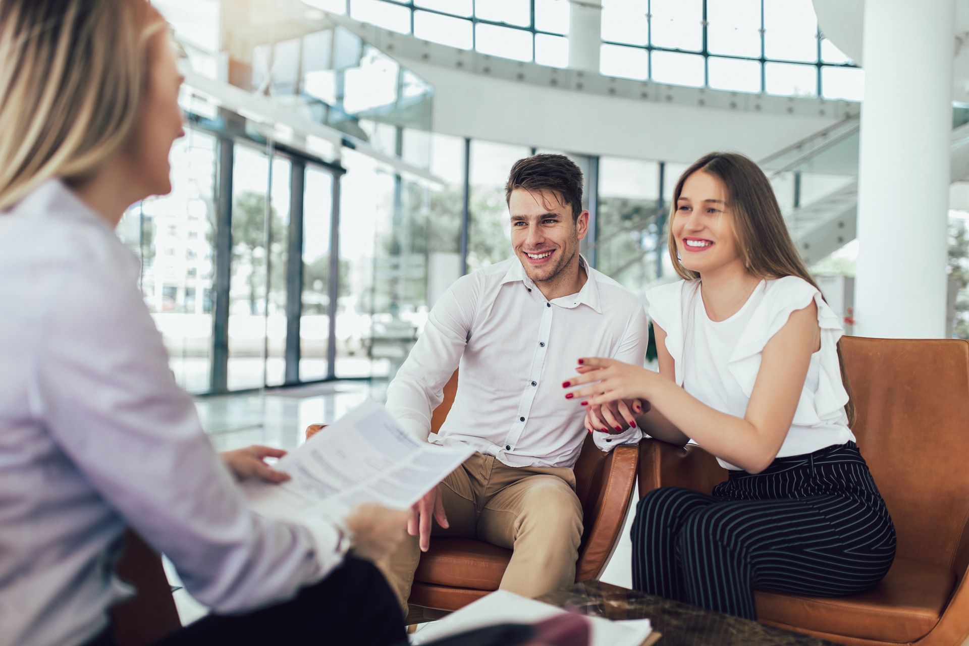 A man and a woman are sitting on a couch talking to a woman.