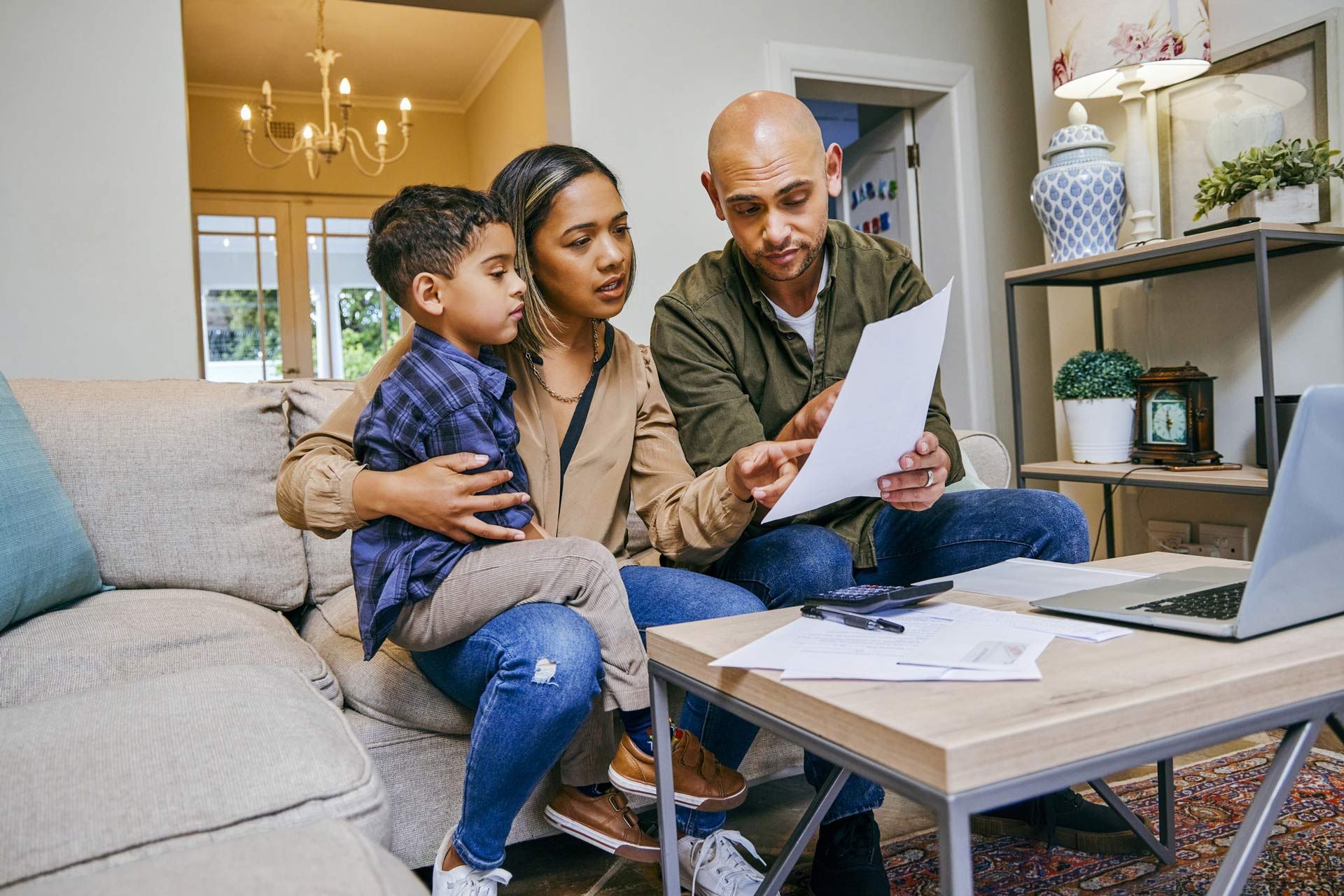 A family is sitting on a couch looking at a piece of paper.