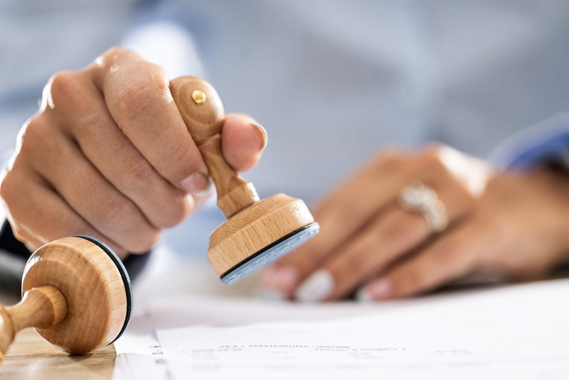 A person is holding a wooden stamp over a piece of paper.