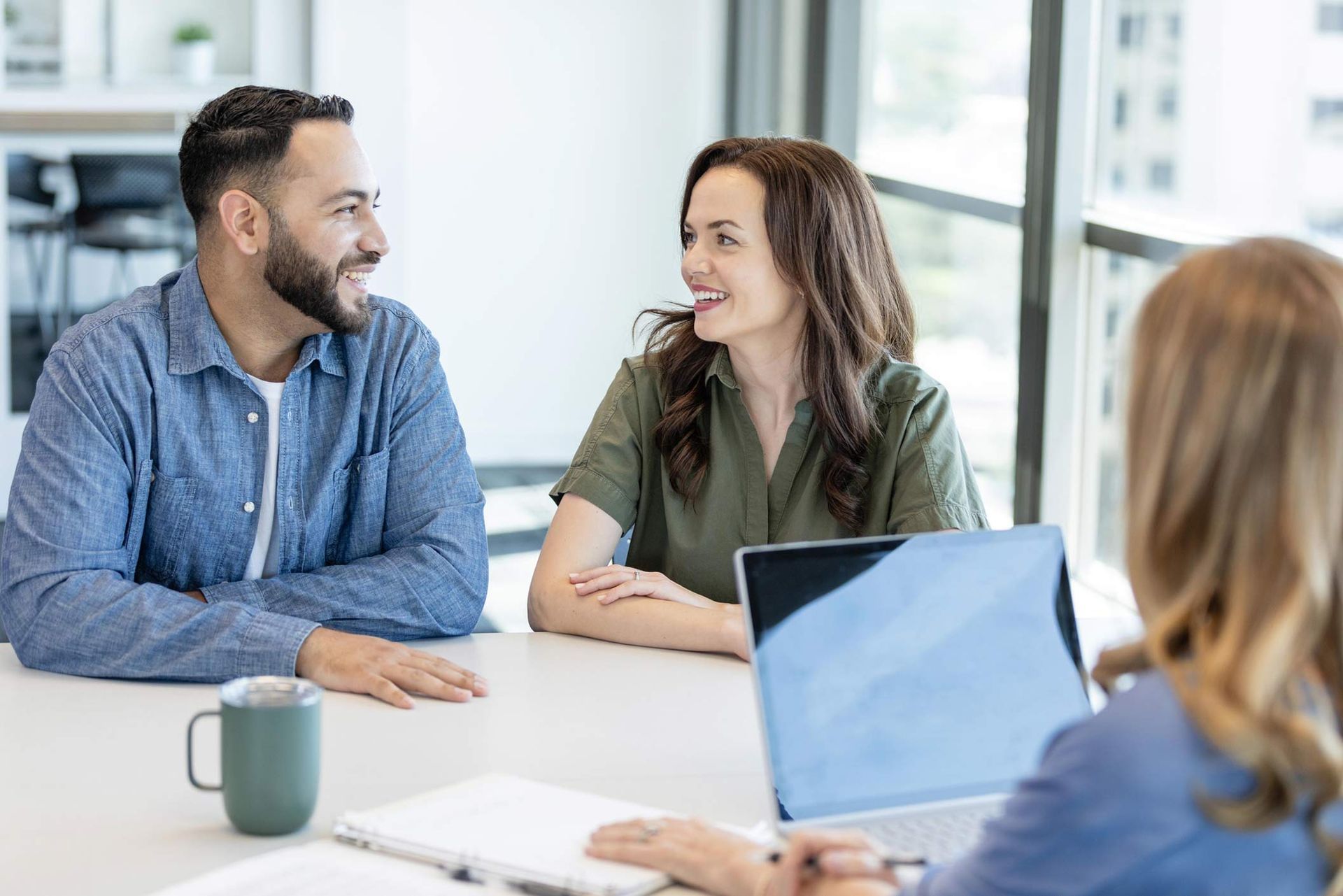 A man and a woman are sitting at a table with a laptop.