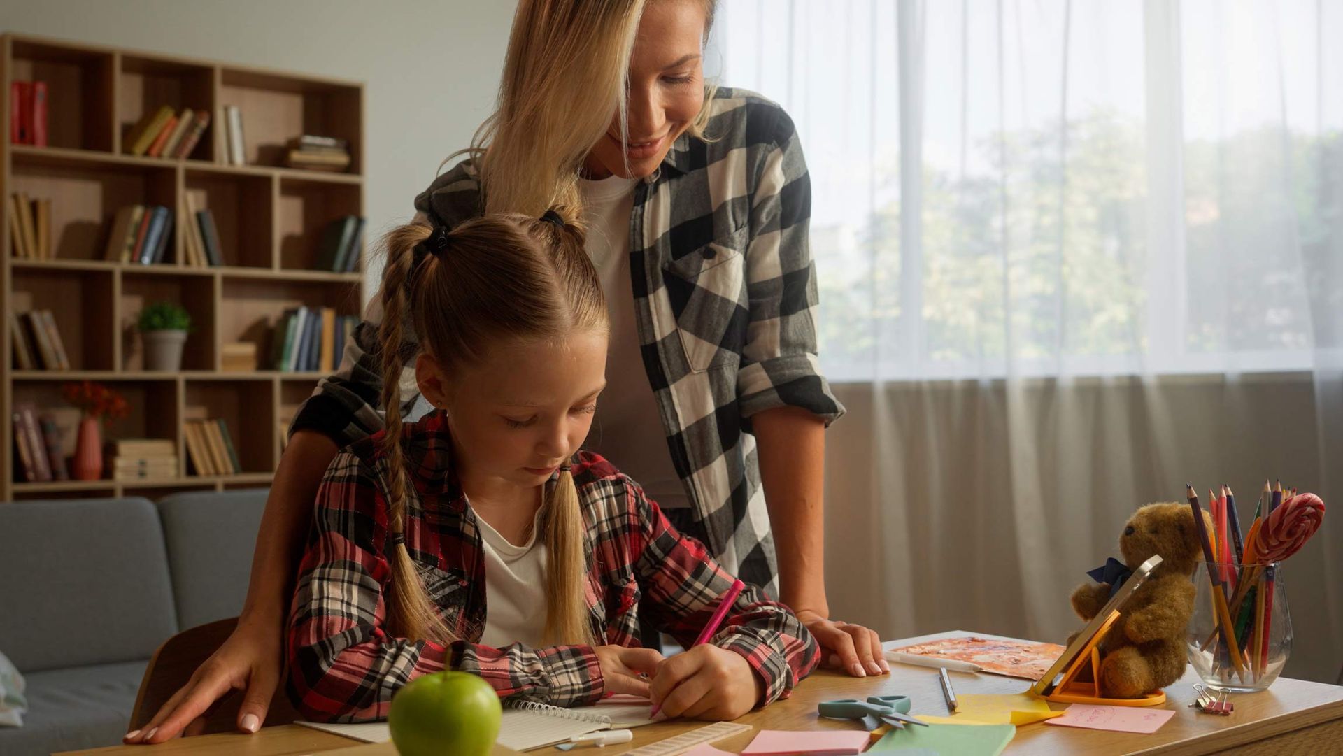 A woman is helping a little girl with her homework.
