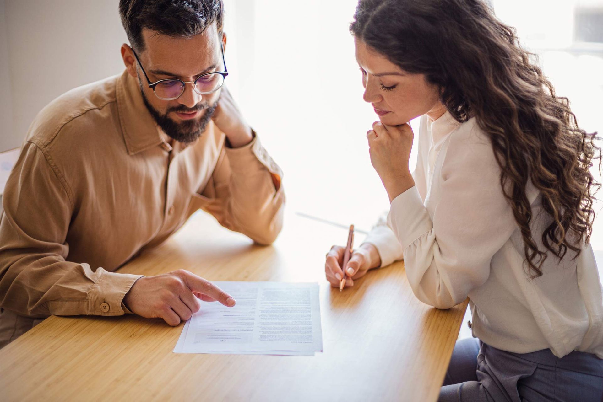A man and a woman are sitting at a table looking at a piece of paper.