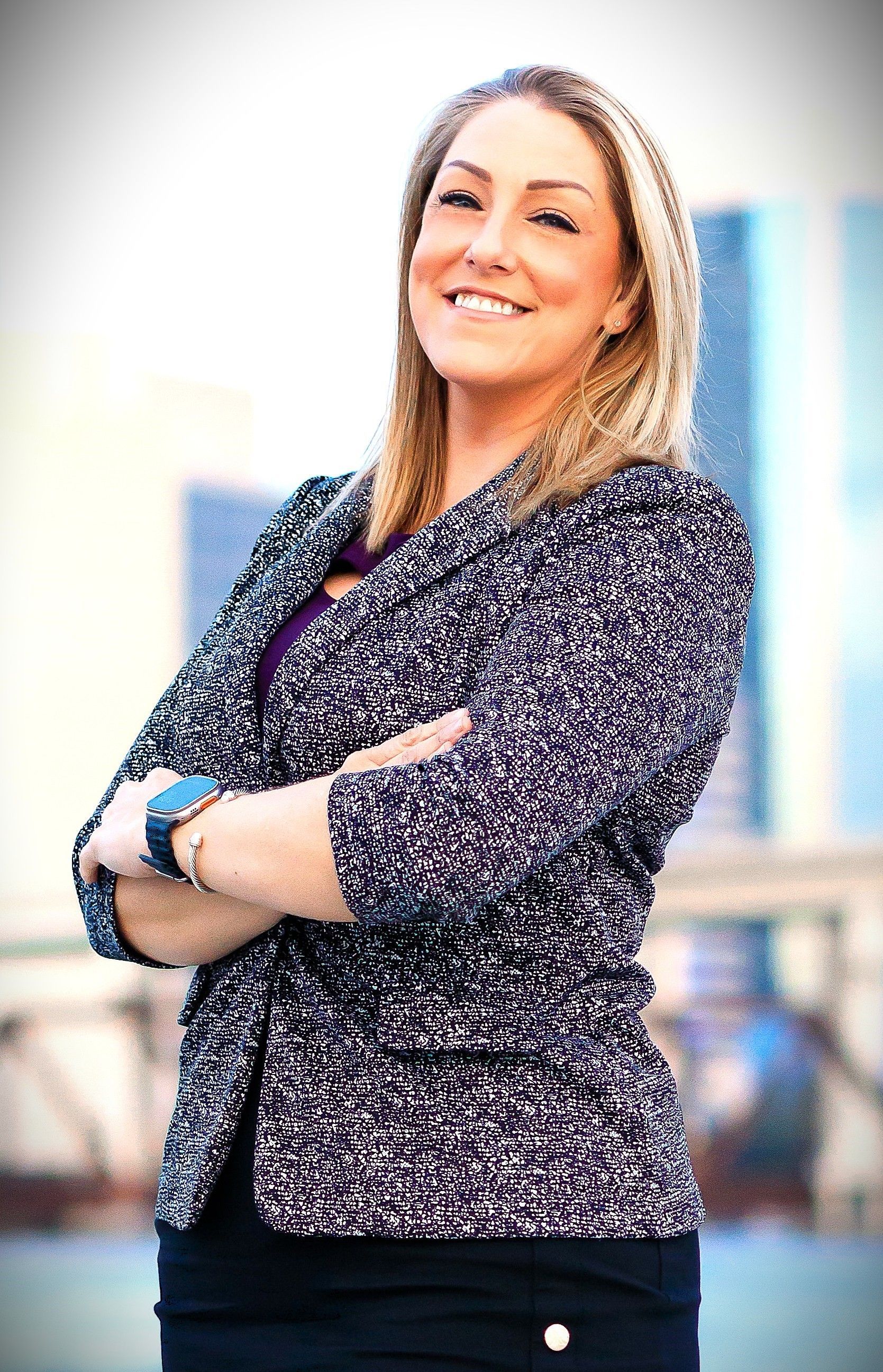A woman wearing a purple shirt and a black jacket is smiling for the camera.