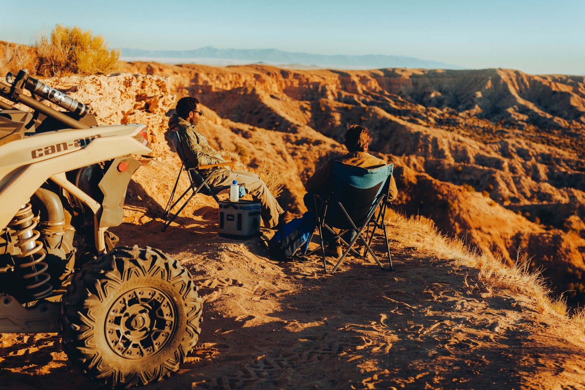 Two men resting on a field after riding their UTVs