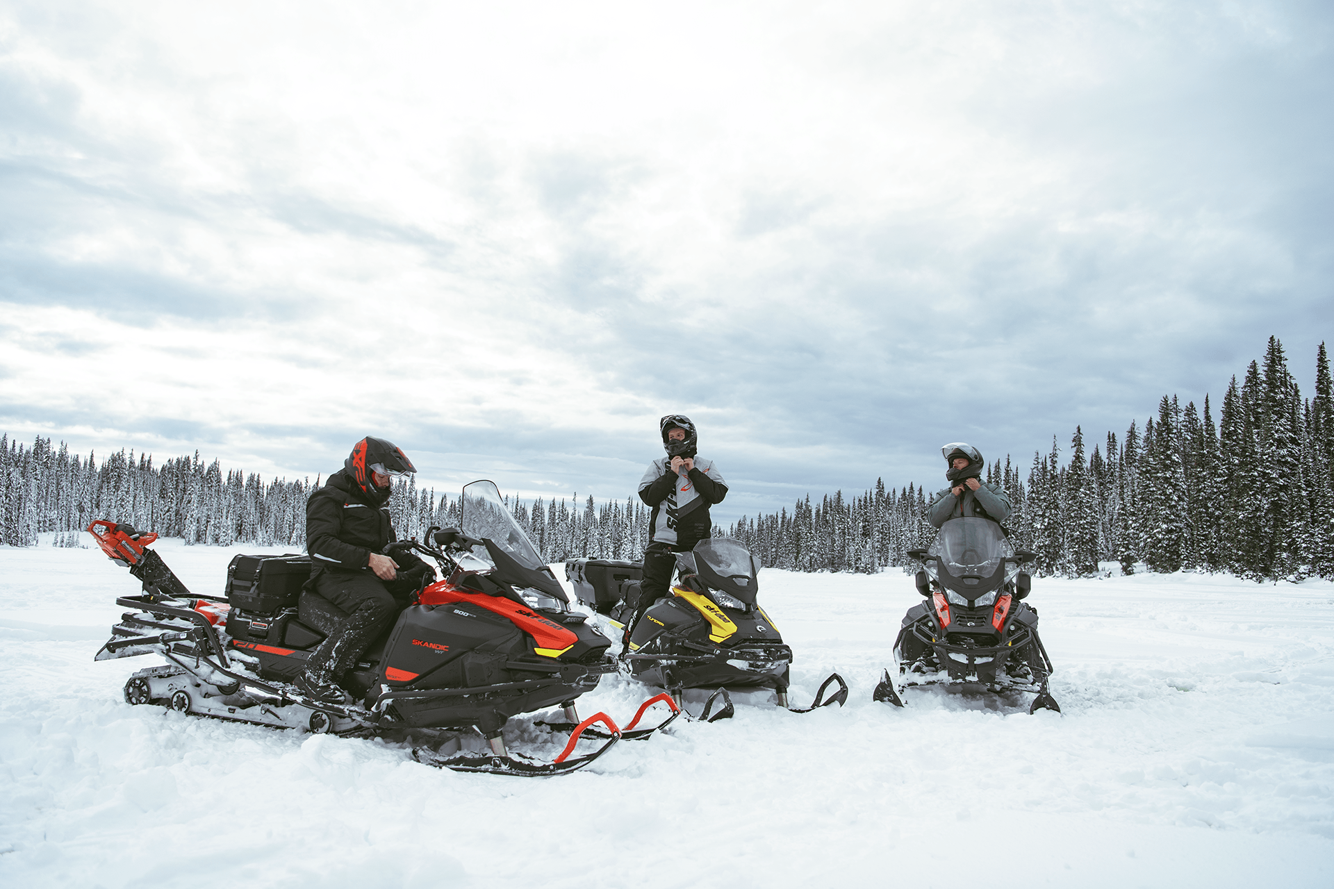 Three riders preparing to ride a snowmobile