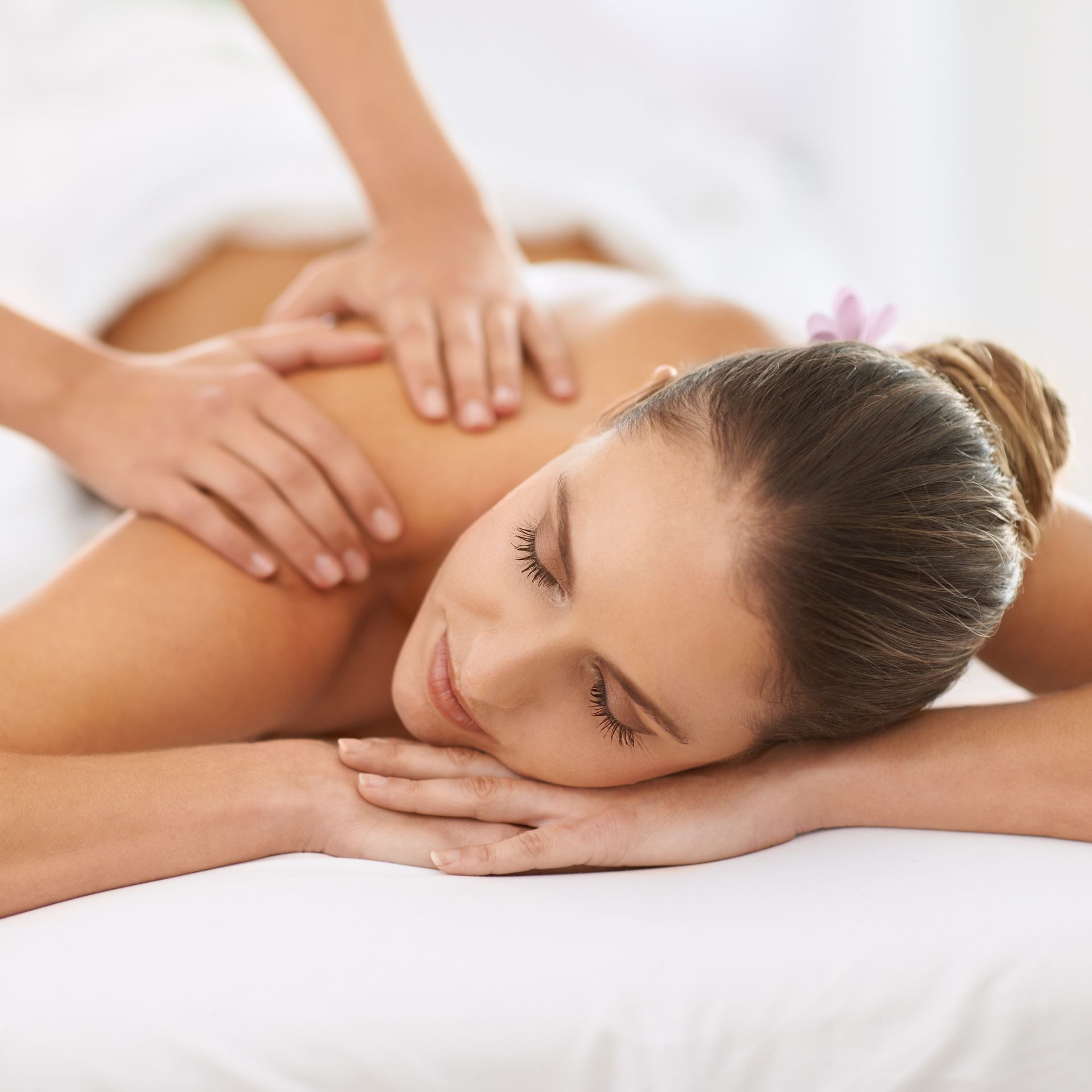 A woman is laying on a bed getting a massage