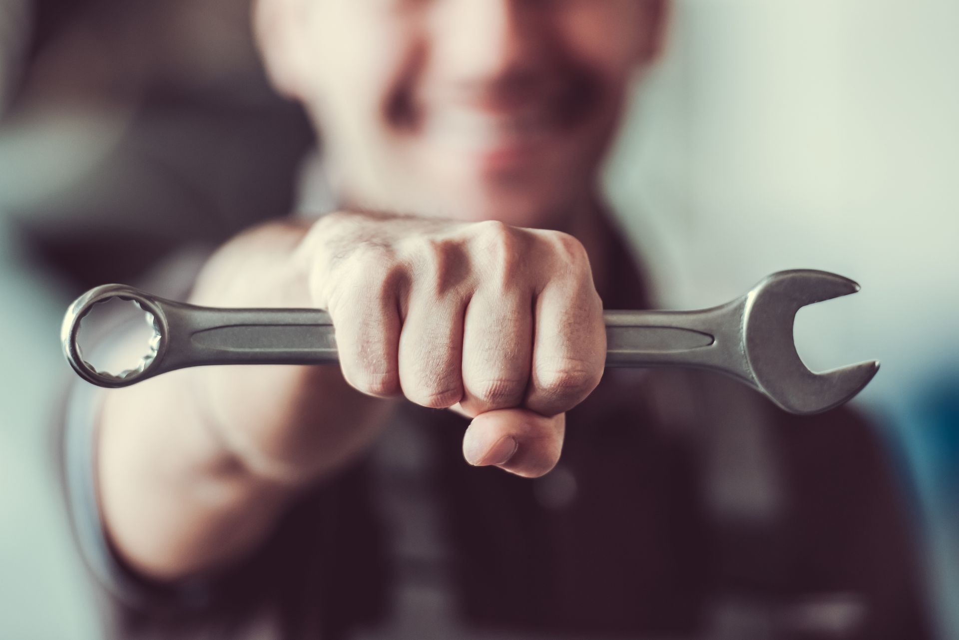 Mechanic holding a wrench in hand, close-up of tool, automotive repair service concept.