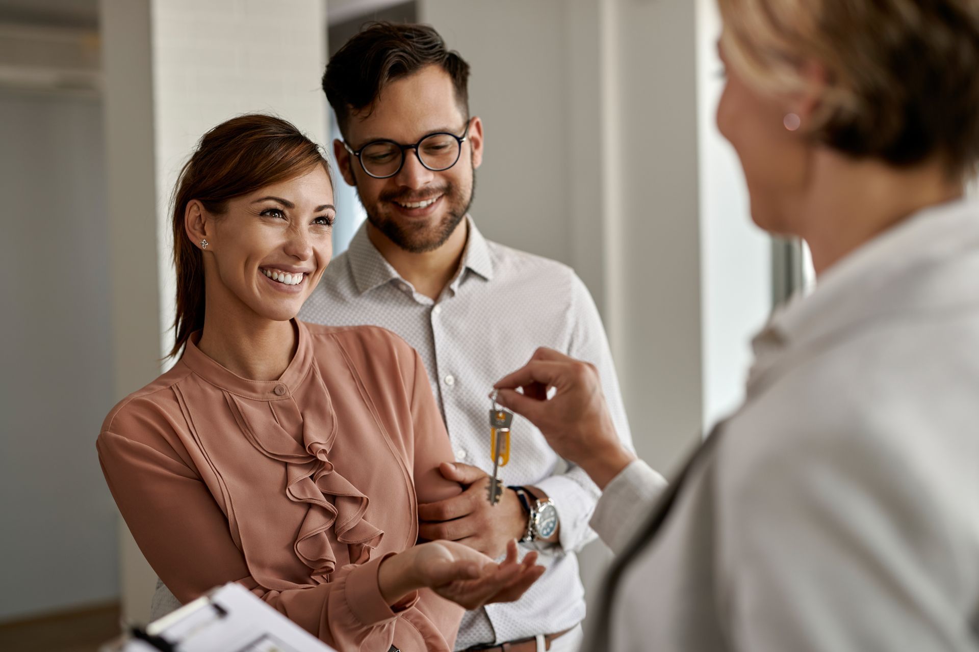 A man and a woman are getting keys from a real estate agent.