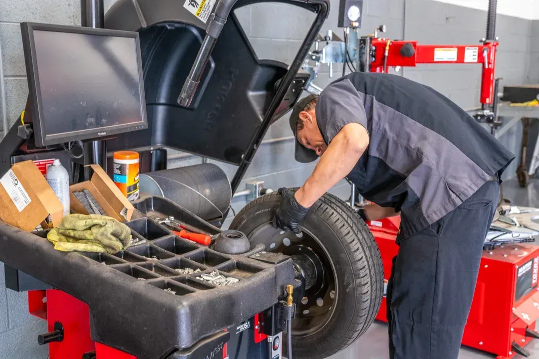 Mechanic balancing a tire on a machine in a garage.