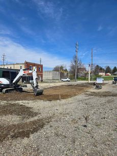 A bulldozer is digging a hole in a gravel lot.