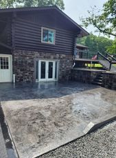 A large log cabin with a concrete patio in front of it.