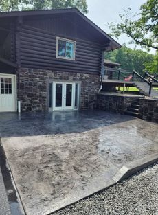 A large log cabin with a concrete patio in front of it.