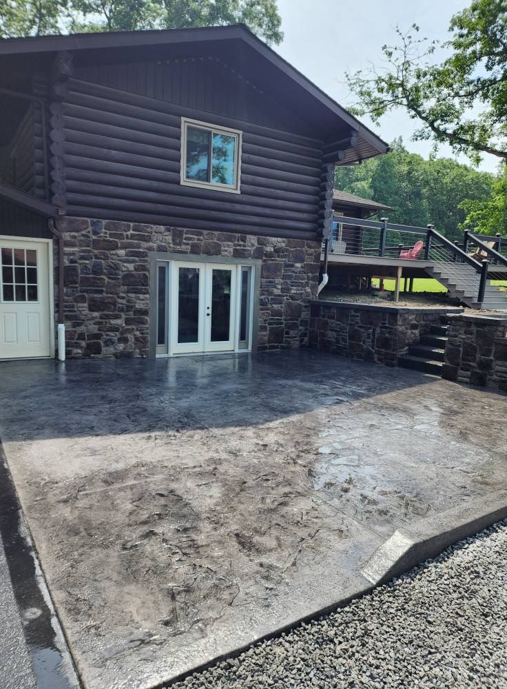 A large log cabin with a concrete patio in front of it.
