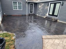 A concrete patio in front of a house with a black door