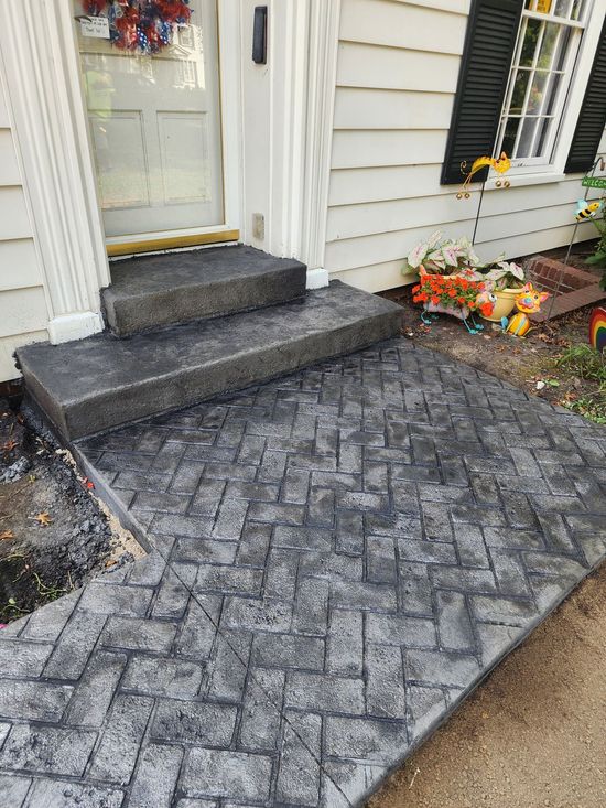 A concrete walkway leading to the front door of a house.
