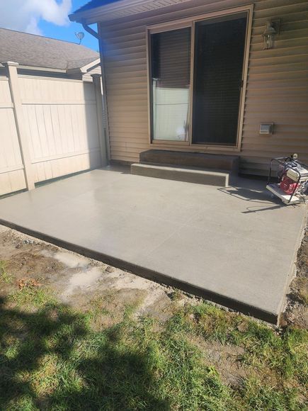A concrete patio is being built in front of a house.