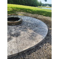 A fire pit is sitting in the middle of a concrete patio.