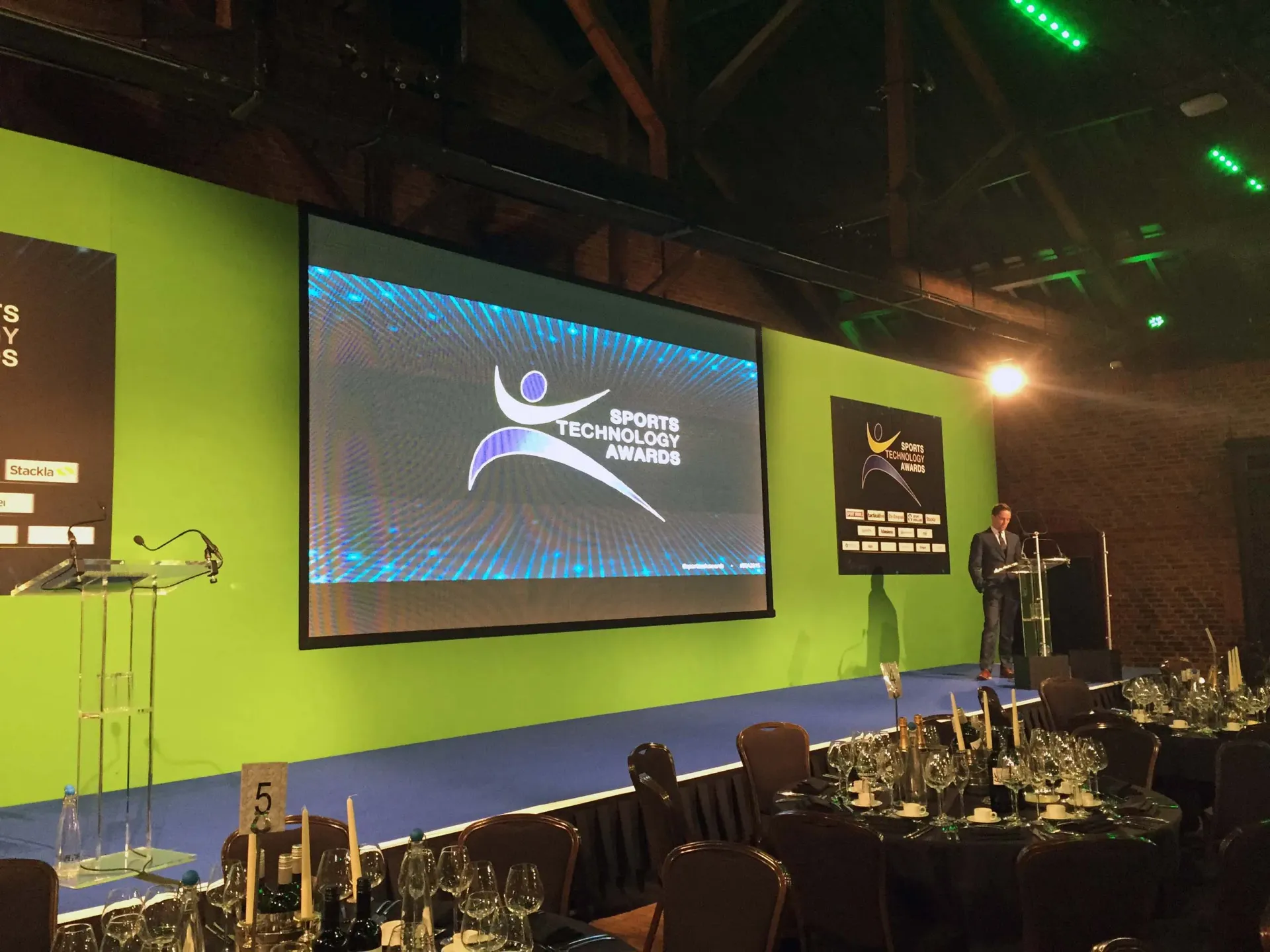 A man stands at a podium in front of a large screen that says World Technology Awards, supplied by Absolute Events 