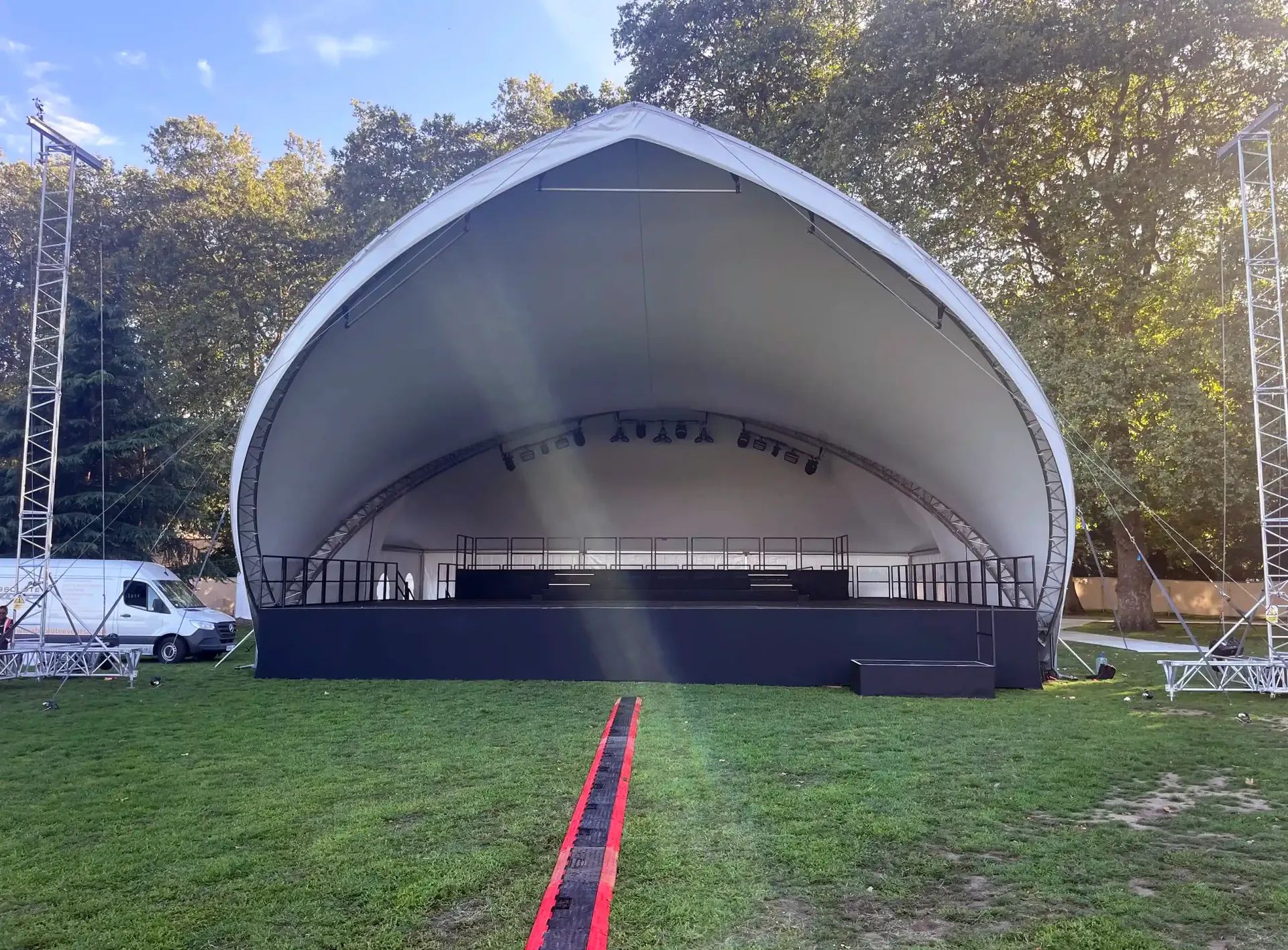 A large stage is sitting in the middle of a grassy field, supplied by Absolute event hire