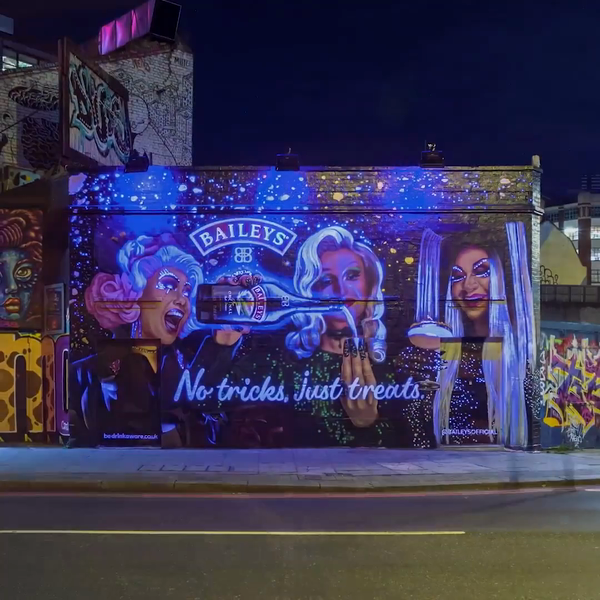 There is a mural on the side of a building that is illuminated  Absolute Events with UV light