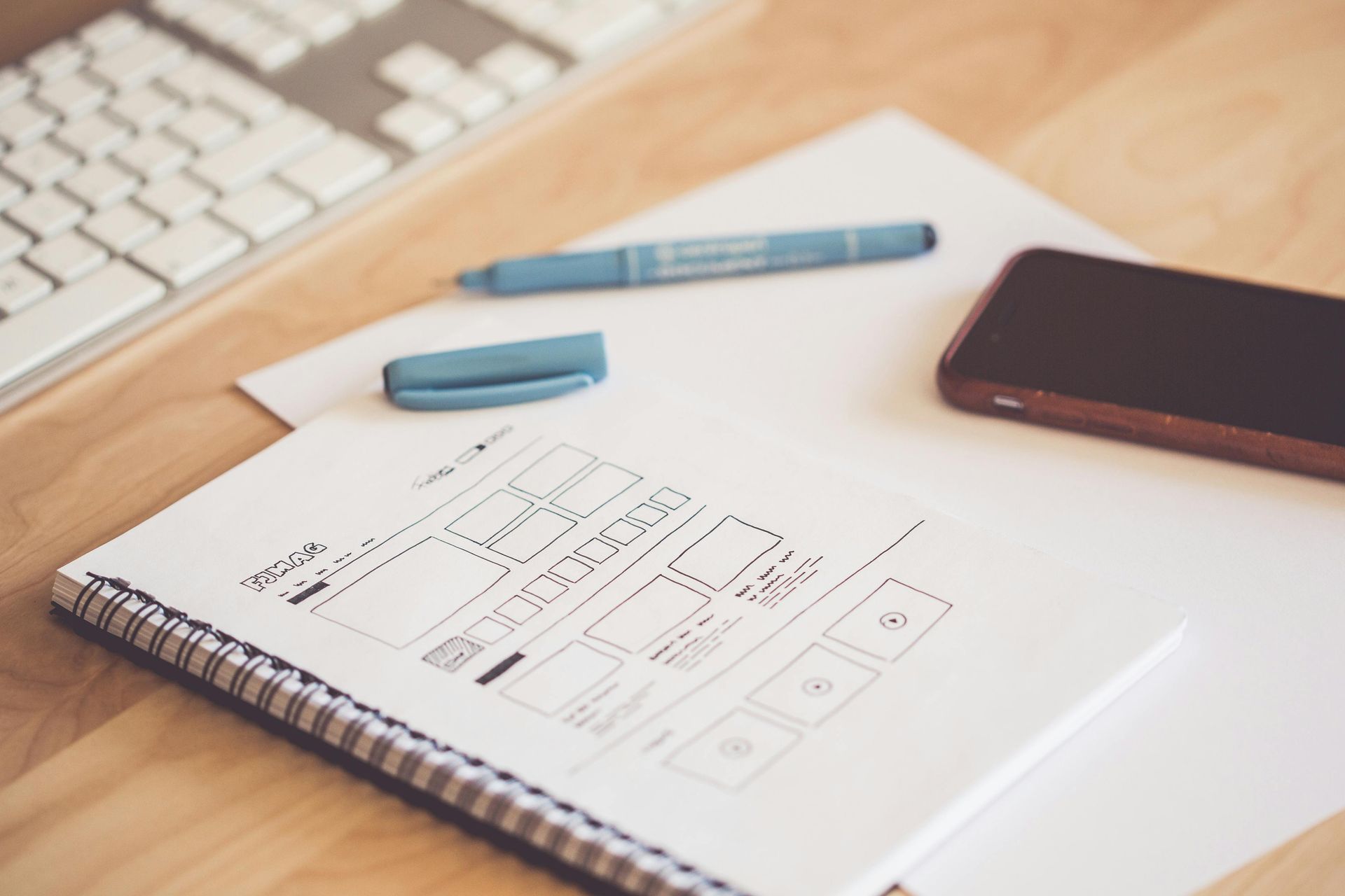 A notebook with a pen and a cell phone on a desk