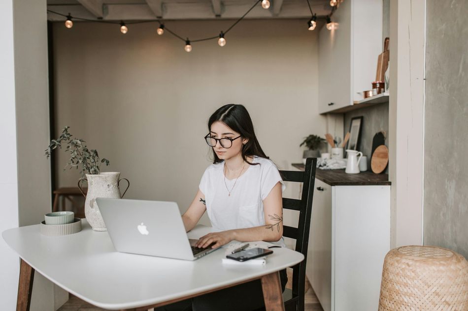 A woman is sitting at a table using a laptop computer.